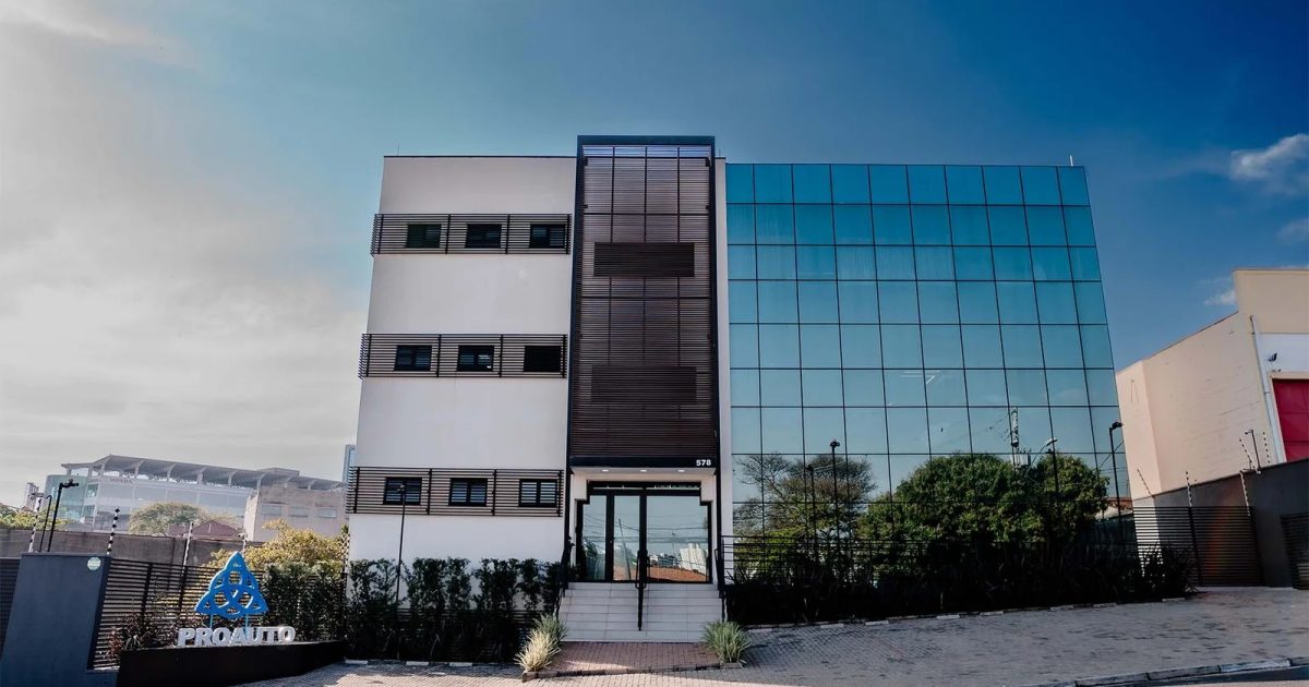 Fachada da sede da PROAUTO, com prédio de vidro e o logotipo da associação na entrada.